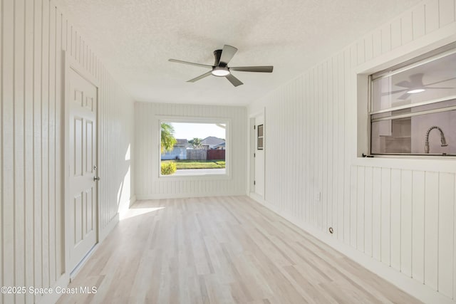 unfurnished room featuring a sink, a textured ceiling, ceiling fan, and wood finished floors