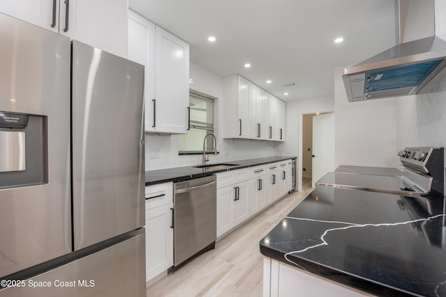 kitchen with a sink, white cabinetry, appliances with stainless steel finishes, and wall chimney range hood