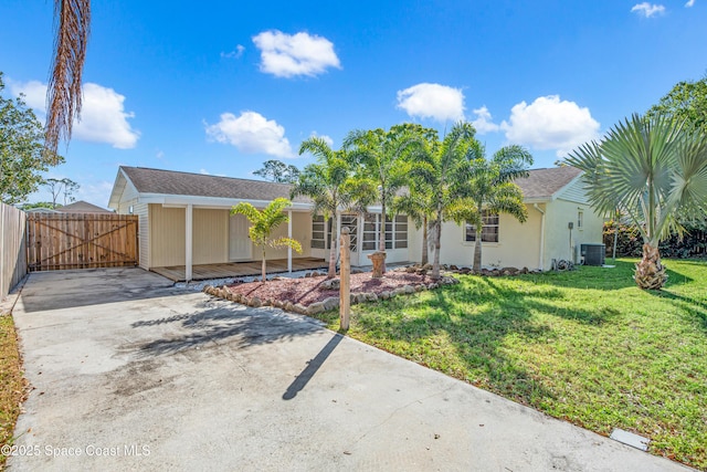 view of front facade featuring stucco siding, a front lawn, driveway, central AC, and fence