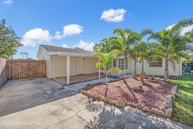 view of front of home featuring an attached carport, fence, a wooden deck, cooling unit, and driveway