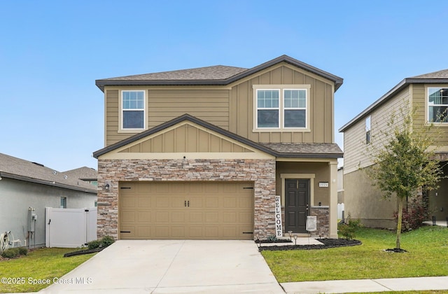 craftsman house with stone siding, board and batten siding, concrete driveway, a front yard, and a garage