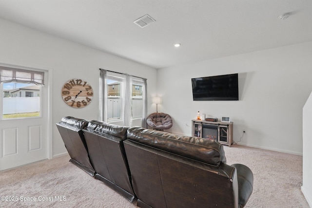 living area with baseboards, visible vents, and light carpet