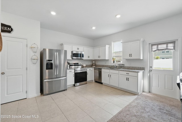 kitchen with a sink, white cabinetry, recessed lighting, stainless steel appliances, and light stone countertops