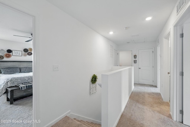 corridor with visible vents, an upstairs landing, baseboards, light colored carpet, and attic access