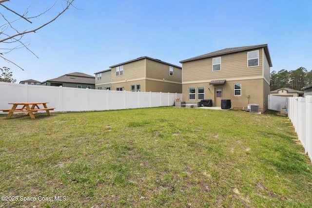 rear view of house featuring stucco siding, a lawn, central AC, and a fenced backyard