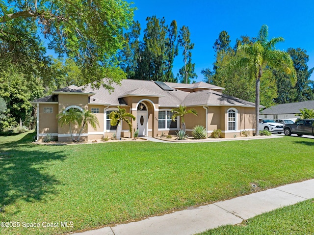 mediterranean / spanish-style house with solar panels, a front lawn, and stucco siding