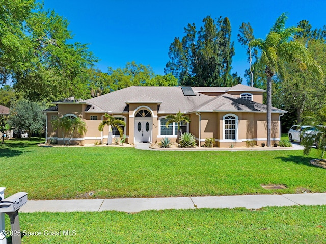 view of front of property featuring stucco siding, a shingled roof, and a front lawn