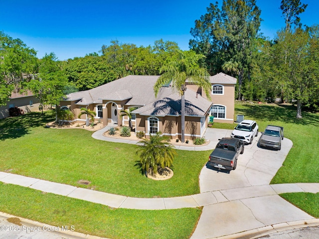 mediterranean / spanish home with a front yard, concrete driveway, roof with shingles, and stucco siding