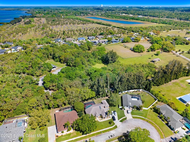 drone / aerial view with a residential view, a water view, and a wooded view