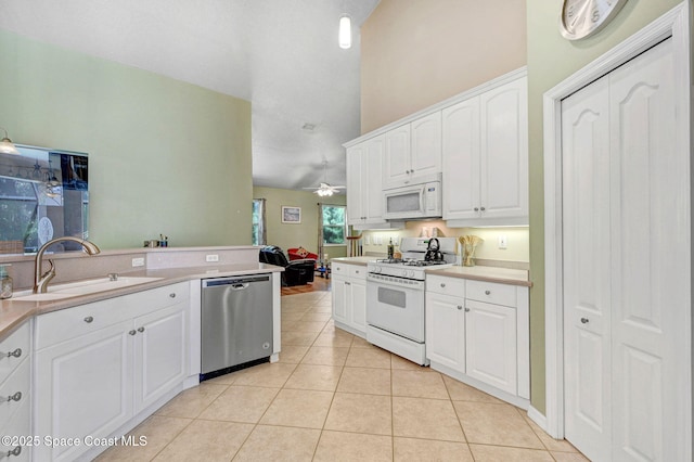 kitchen with light countertops, light tile patterned flooring, white cabinets, white appliances, and a sink