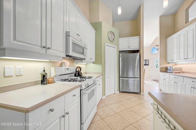 kitchen featuring white appliances, light tile patterned floors, hanging light fixtures, light countertops, and white cabinetry