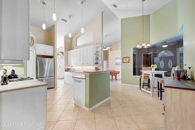 kitchen featuring ceiling fan with notable chandelier, open shelves, freestanding refrigerator, white cabinets, and light tile patterned floors