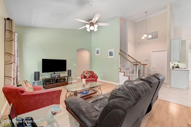 living area featuring visible vents, baseboards, arched walkways, stairs, and light wood-style floors