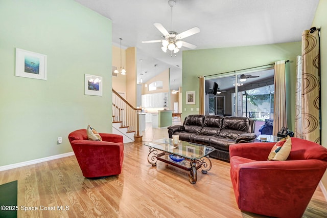 living room featuring wood finished floors, baseboards, high vaulted ceiling, stairs, and ceiling fan with notable chandelier