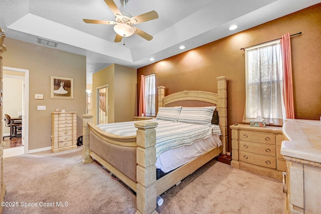 bedroom featuring visible vents, baseboards, connected bathroom, a raised ceiling, and light colored carpet