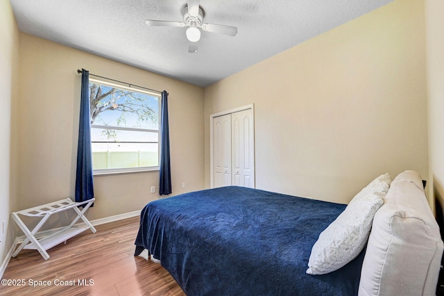 bedroom featuring wood finished floors, baseboards, a closet, and a textured ceiling