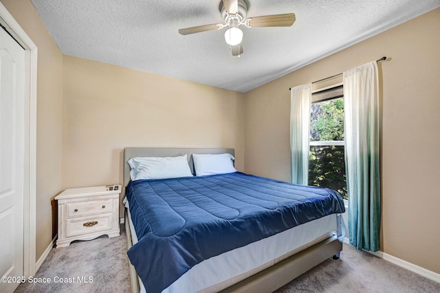 carpeted bedroom featuring baseboards, a textured ceiling, and ceiling fan