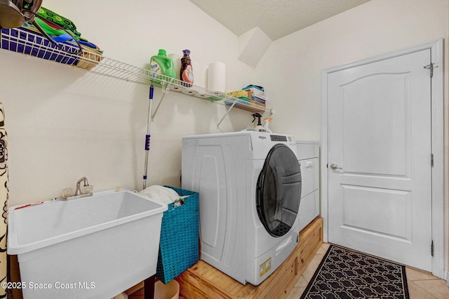 laundry area with a textured ceiling, laundry area, washer / clothes dryer, and a sink