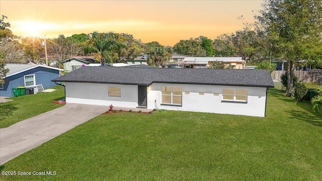 view of front facade with a front lawn, roof with shingles, and stucco siding