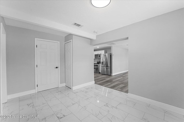 unfurnished room with visible vents, baseboards, a textured ceiling, and marble finish floor