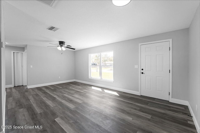 unfurnished living room with dark wood finished floors, visible vents, ceiling fan, and baseboards