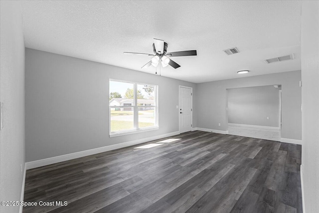 empty room featuring visible vents, baseboards, and dark wood-style flooring