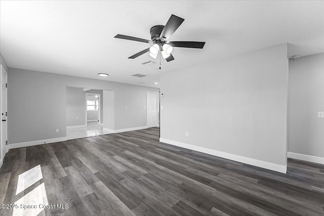 empty room featuring visible vents, baseboards, a textured ceiling, and dark wood-style flooring