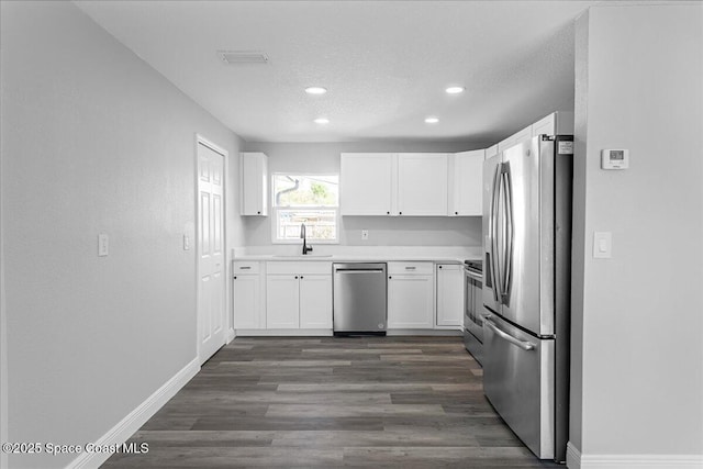 kitchen featuring a sink, stainless steel appliances, a textured ceiling, and white cabinets