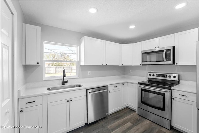 kitchen with white cabinets, appliances with stainless steel finishes, dark wood-type flooring, and a sink