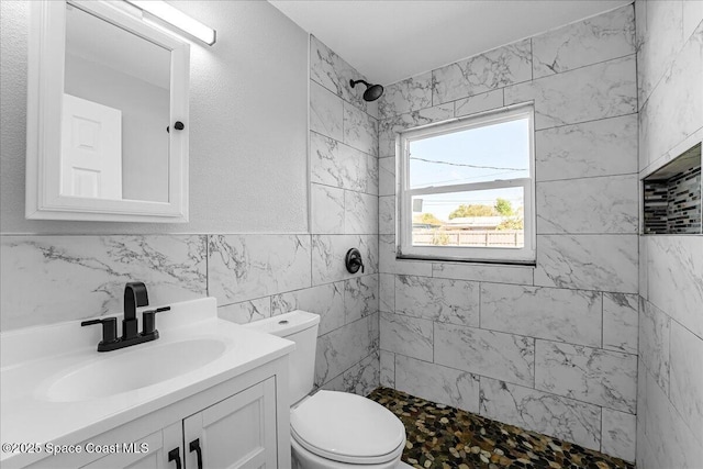 bathroom with tiled shower, toilet, tile walls, and vanity