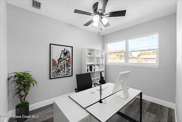 office area featuring dark wood finished floors, baseboards, visible vents, and ceiling fan