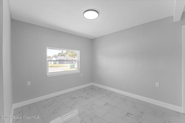 unfurnished room with baseboards, marble finish floor, and a textured ceiling