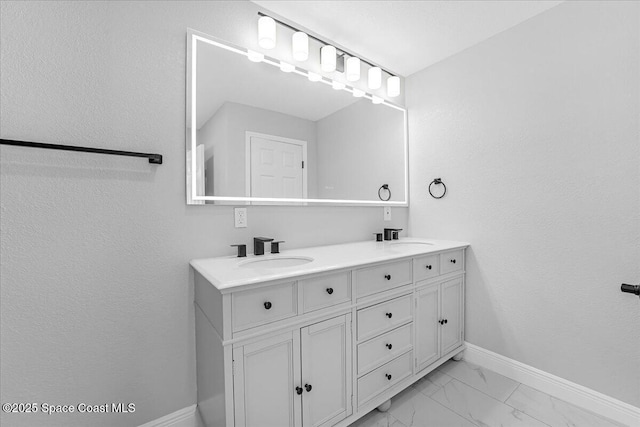 bathroom featuring double vanity, baseboards, marble finish floor, and a sink