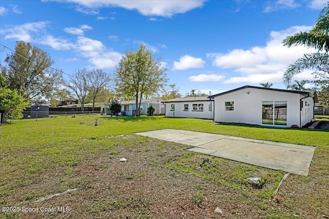 back of property with a lawn, fence, and stucco siding