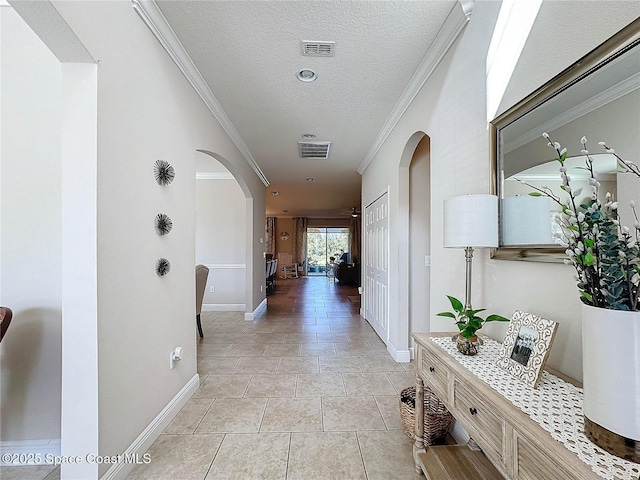 hallway featuring visible vents, arched walkways, a textured ceiling, and ornamental molding