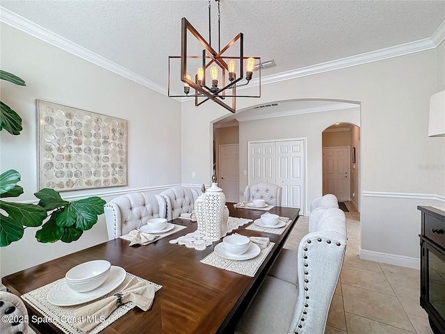 dining room with light tile patterned floors, arched walkways, a textured ceiling, and ornamental molding