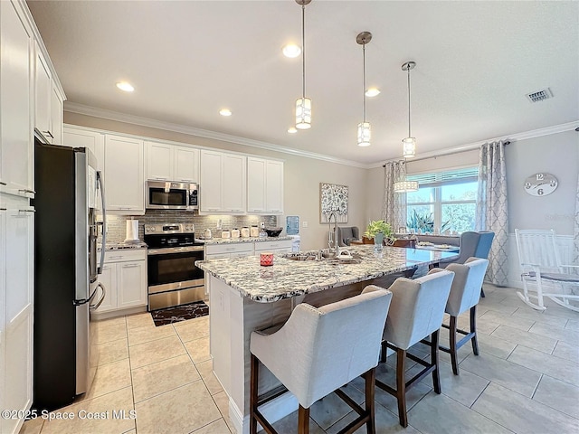 kitchen with visible vents, a breakfast bar, ornamental molding, appliances with stainless steel finishes, and a sink