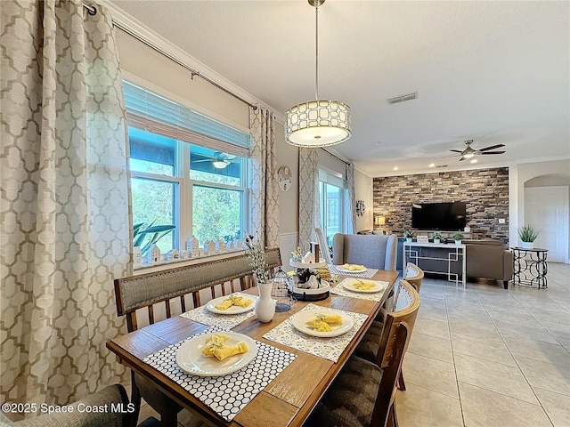 dining space featuring visible vents, ceiling fan, ornamental molding, light tile patterned floors, and arched walkways