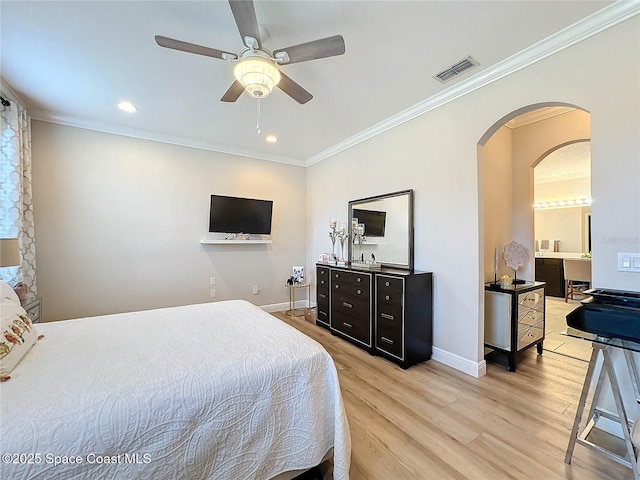 bedroom with crown molding, visible vents, arched walkways, and light wood-type flooring