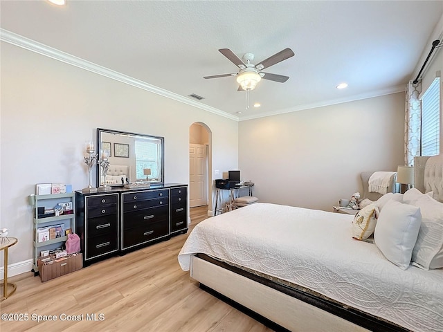 bedroom featuring visible vents, baseboards, arched walkways, crown molding, and light wood-type flooring