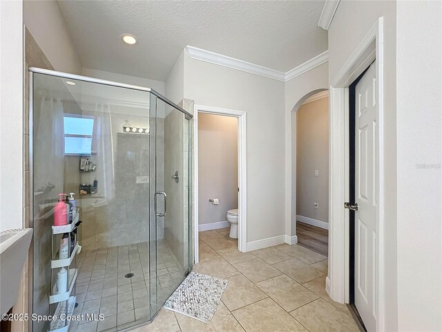 full bath with baseboards, toilet, a shower stall, and a textured ceiling