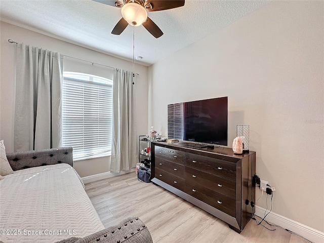 bedroom featuring ceiling fan, baseboards, a textured ceiling, and light wood-style flooring