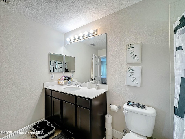 bathroom featuring vanity, toilet, a textured wall, and a textured ceiling