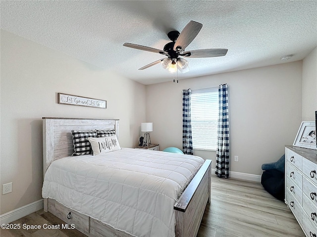 bedroom with ceiling fan, light wood-style floors, baseboards, and a textured ceiling