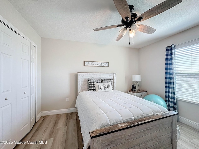 bedroom with light wood-style flooring, multiple windows, and a textured ceiling