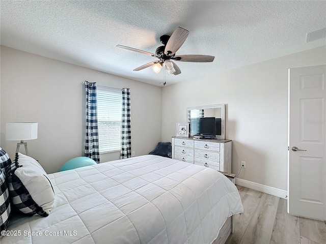 bedroom with visible vents, a ceiling fan, a textured ceiling, light wood-style floors, and baseboards