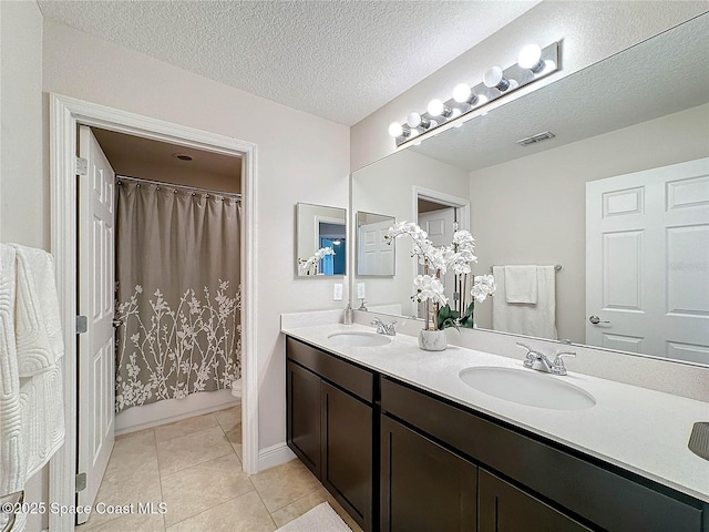 bathroom with tile patterned floors, toilet, visible vents, and a sink