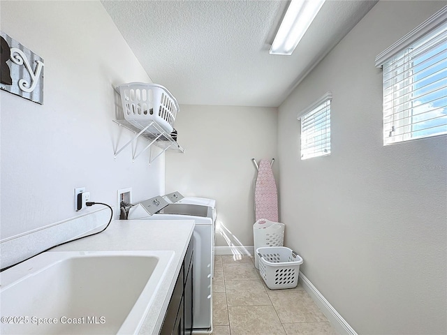 laundry room featuring light tile patterned floors, washing machine and clothes dryer, laundry area, a sink, and a textured ceiling