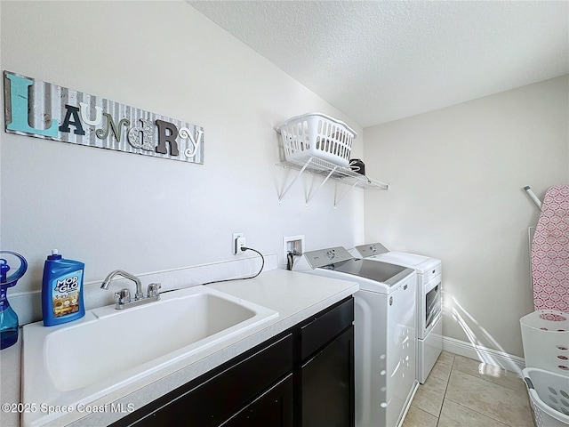 washroom with washing machine and clothes dryer, light tile patterned floors, cabinet space, a textured ceiling, and a sink