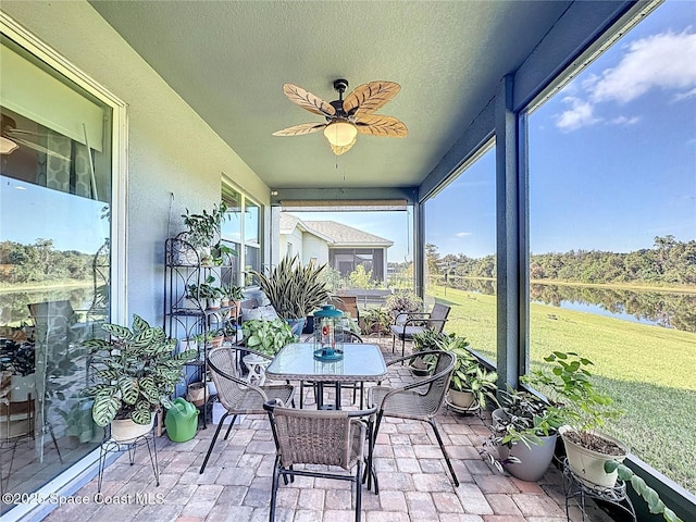 sunroom featuring plenty of natural light, ceiling fan, and a water view